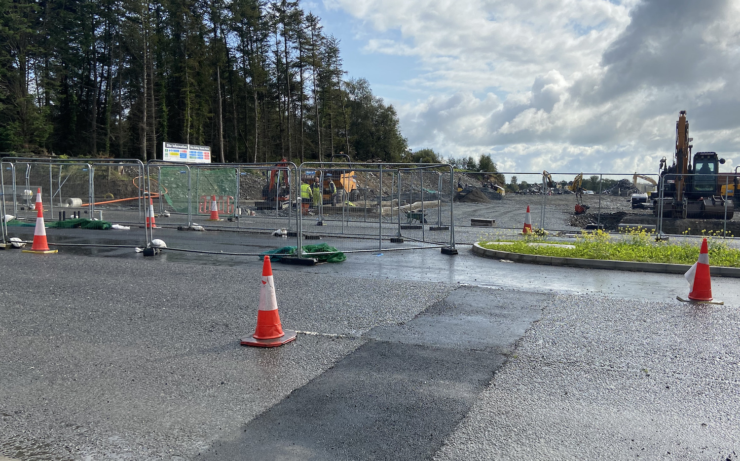 Looking across two lanes coned down to
                          one. A new right-turn lane is visible in the
                          central reservation. Building site beyond.