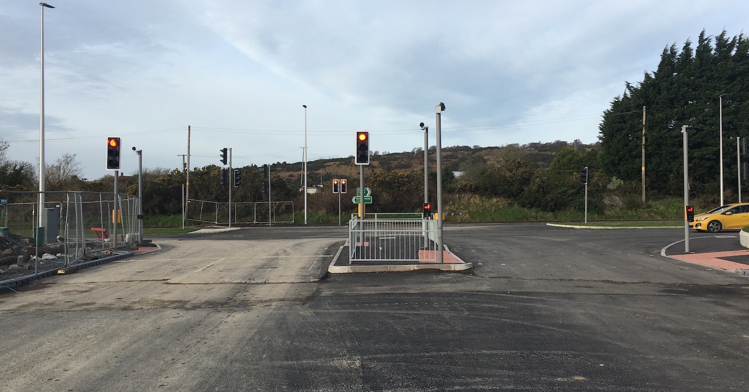 View from the centre of a road towards a
                          T-junction with a dual-carriageway about 100
                          metres ahead and traffic signals