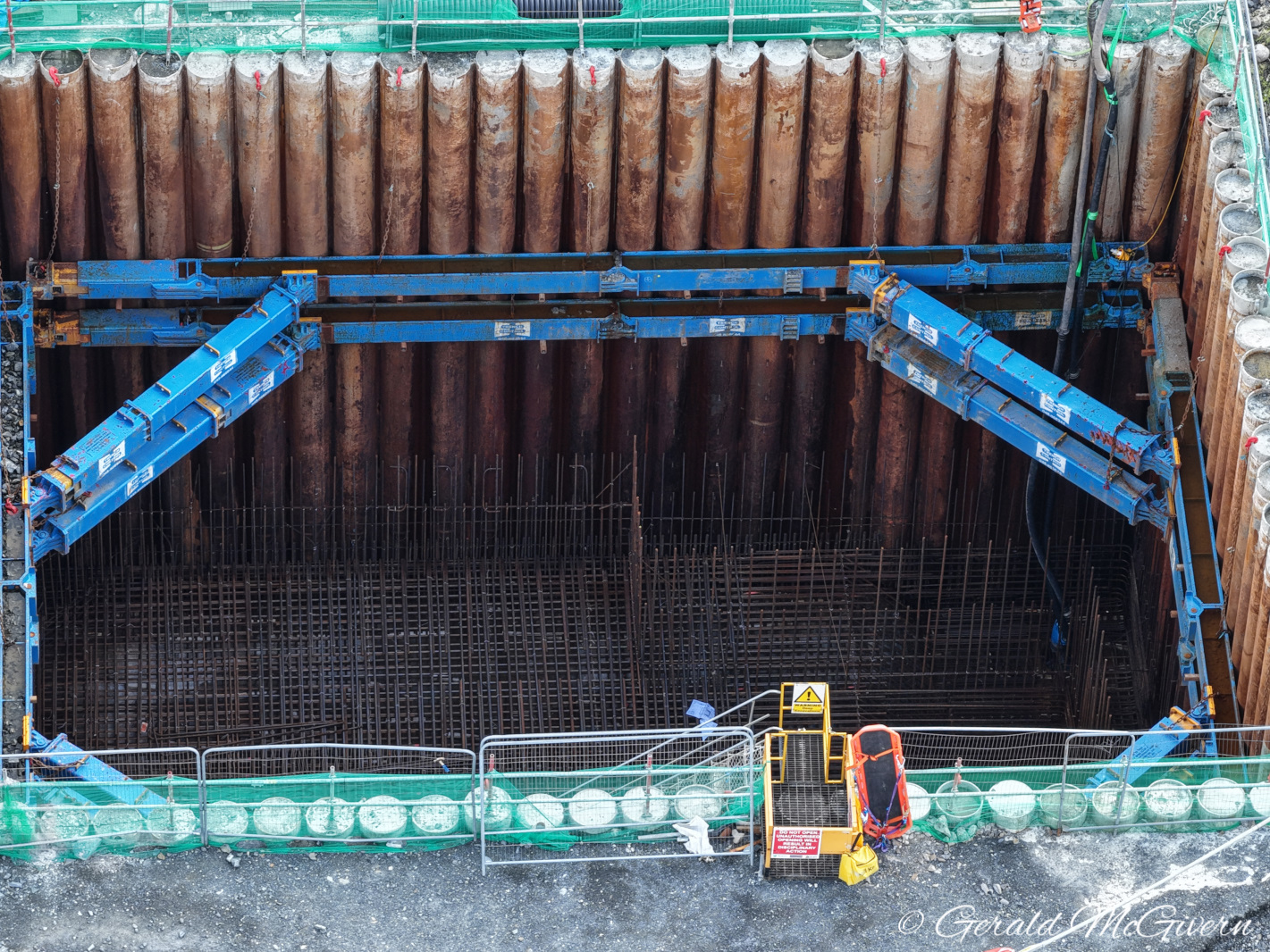 Looking down into a deep, dark hole
                          surrounded by steel piles, with a blue
                          supporting frame holding it up